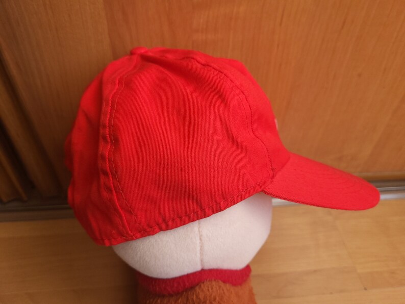 May include: A red baseball cap with a curved brim. The cap is made of a soft, cotton fabric.
