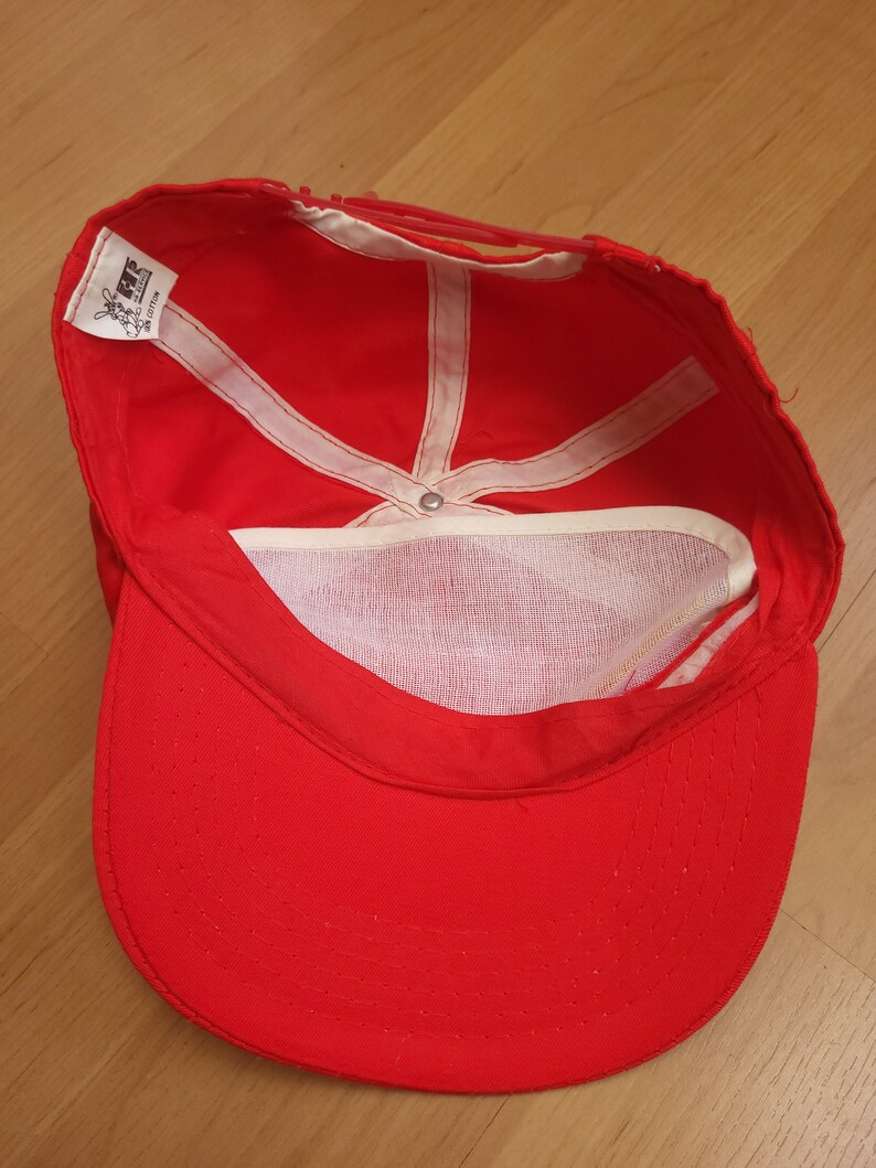May include: Red baseball cap with a white mesh lining and a white label that says "LEVIS 100% COTTON MADE IN TAIWAN".