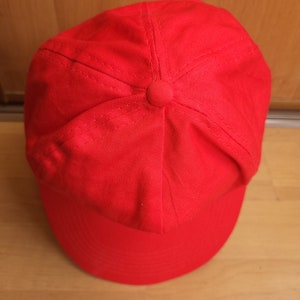 May include: A solid red baseball cap with a curved brim.