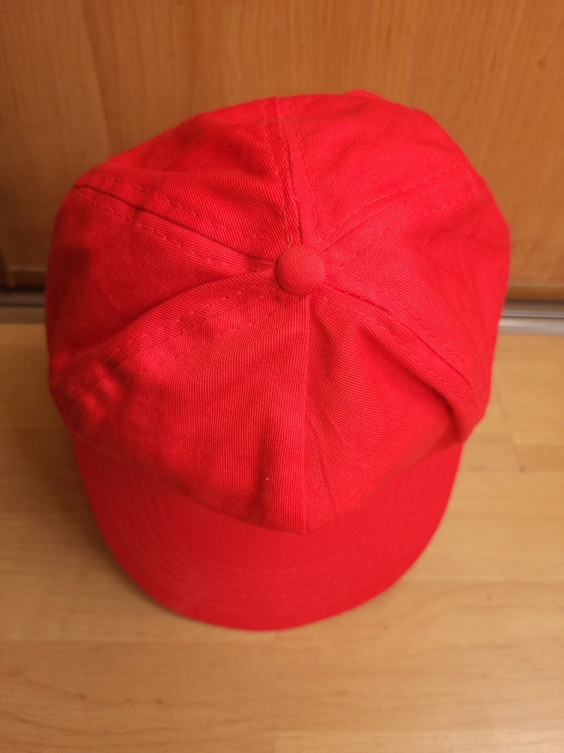 May include: A solid red baseball cap with a curved brim.