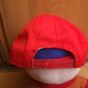 May include: A red baseball cap with a blue underside and a red adjustable strap.