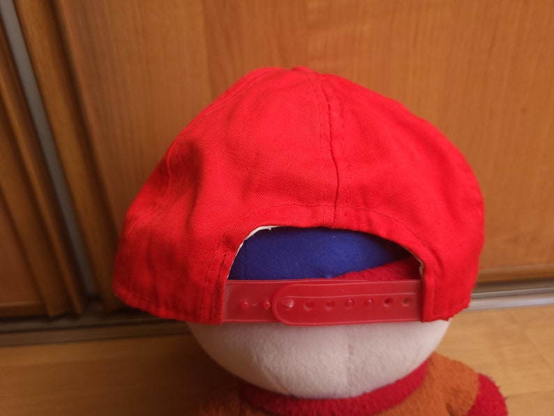 May include: A red baseball cap with a blue underside and a red adjustable strap.