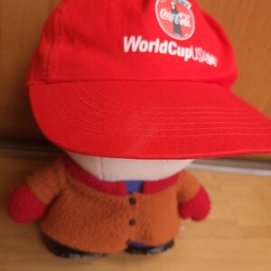 May include: Red baseball cap with a white Coca-Cola logo and the text "World Cup USA 94" in white.