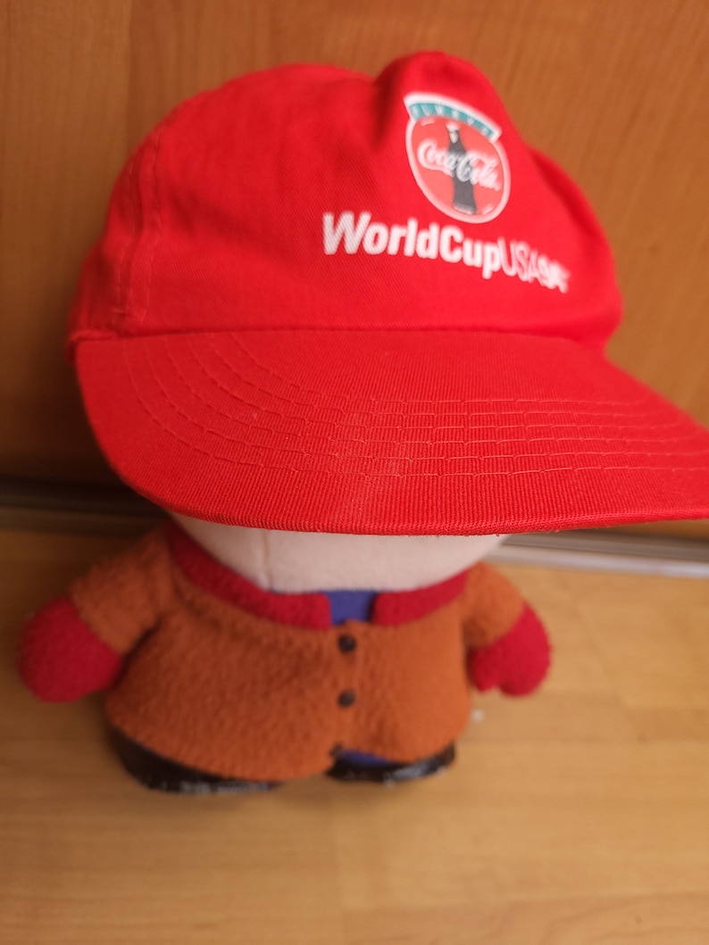 May include: Red baseball cap with a white Coca-Cola logo and the text "World Cup USA 94" in white.