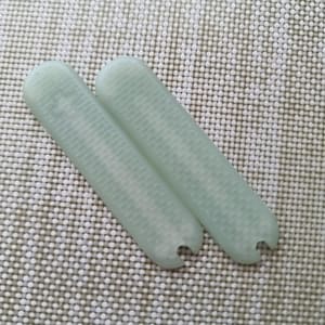 Puede incluir: Dos objetos rectangulares de color verde p&aacute;lido con extremos redondeados y una superficie texturizada. Un extremo de cada objeto tiene un peque&ntilde;o recorte semicircular. Los objetos est&aacute;n sobre una superficie texturizada blanquecina.
