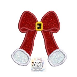 May include: Red and white Christmas bow with a gold buckle. The bow is designed for embroidery.