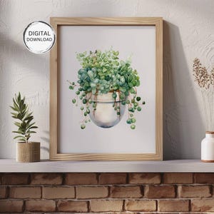 May include: Watercolor print of a hanging succulent plant in a white pot, framed in a light wood frame. The artwork features shades of green and blue-green, with the text "DIGITAL DOWNLOAD" in a circle in the upper left corner.
