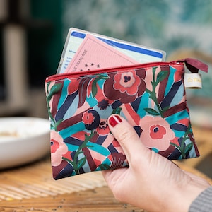 May include: A colorful floral patterned zippered pouch with a red, white, and blue card inside. The pouch is made of fabric and has a zipper closure.