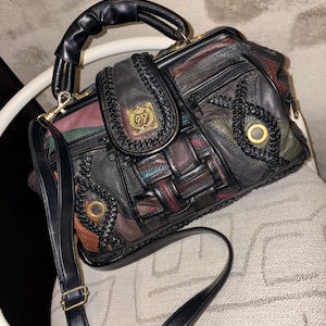 May include: A vintage patchwork leather handbag with a top handle and a detachable shoulder strap. The bag features a variety of colors, including black, brown, red, and green. Gold-toned hardware accents the bag, and a decorative emblem is on the front.