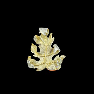 Può includere: Spilla a forma di foglia color oro con dettagli color argento. La spilla presenta un motivo a venature dettagliato ed è ambientata su uno sfondo nero. Il design a foglia è un accessorio ispirato alla natura.