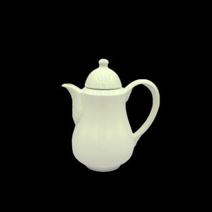 May include: A cream-colored ceramic teapot with a lid and a curved handle. The teapot has a spout for pouring and a rounded body. The lid has a small knob on top. The teapot is set against a black background.
