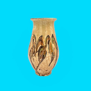 May include: A beige ceramic vase with a flared top and a rounded body. The vase features abstract brown, green, and orange painted designs. The vase is a decorative item.