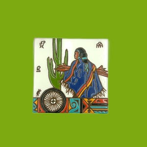 May include: Square ceramic tile featuring a Native American figure in a blue shawl, standing near a green cactus. The tile has a white background with geometric patterns and symbols. The tile is set against a green background.