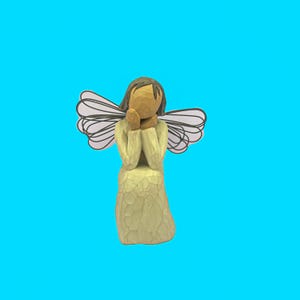 May include: A carved wooden angel figurine with a light green dress and brown hair. The angel has folded hands and white and black patterned wings. The figurine is set against a bright blue background.