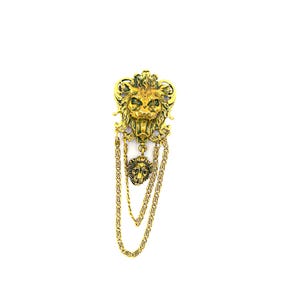 May include: A gold-colored lion head brooch with dangling chains. The brooch features a detailed lion's face with a mane and a smaller lion pendant hanging from the chains. The design is ornate and vintage-inspired.