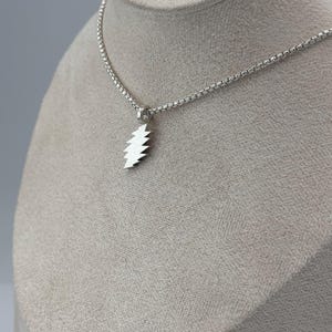 May include: A silver chain necklace with a silver lightning bolt pendant.
