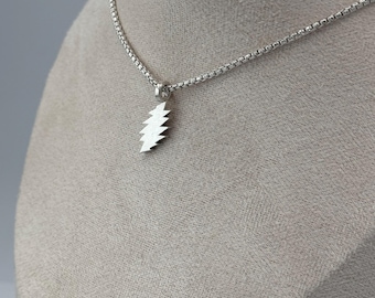 May include: A silver chain necklace with a silver lightning bolt pendant.