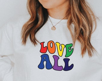 Può includere: Felpa bianca con una grafica "LOVE ALL" arcobaleno.
