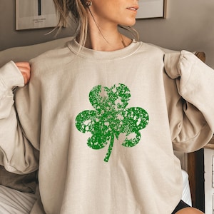 May include: A beige sweatshirt with a green distressed shamrock design.