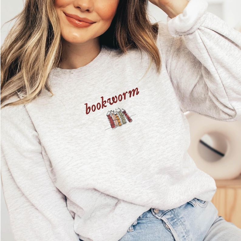 May include: A gray sweatshirt with the text "bookworm" in red lettering and a small illustration of a stack of colorful books.
