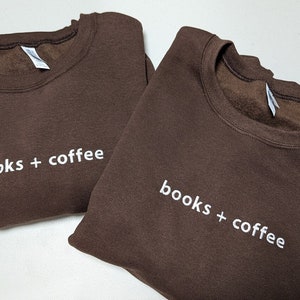 May include: Two brown sweatshirts with white text that reads "books + coffee" on each.