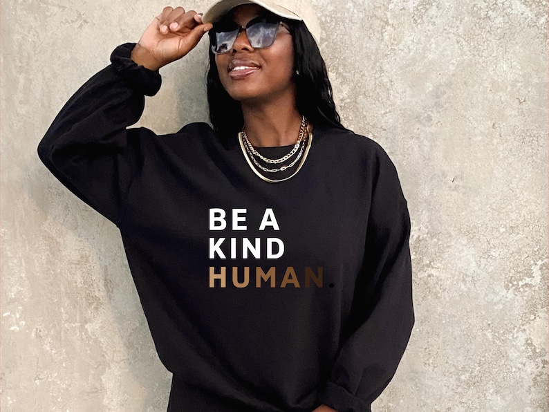 May include: A black sweatshirt with the text "BE A KIND HUMAN." in white and gold lettering.