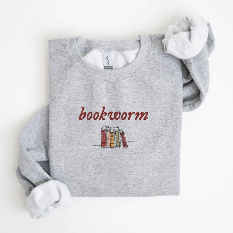 May include: Gray sweatshirt with the text "bookworm" in red cursive lettering and a small illustration of a stack of books below the text.