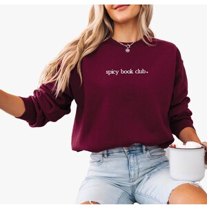 May include: A maroon sweatshirt with the text "spicy book club." embroidered in white on the front.