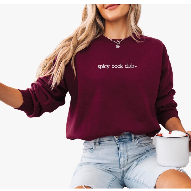 May include: A maroon sweatshirt with the text "spicy book club." embroidered in white on the front.