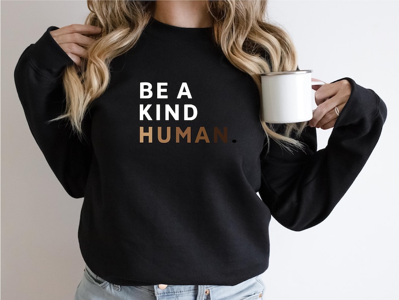 May include: A black sweatshirt with the text "BE A KIND HUMAN." in white and brown lettering.