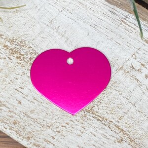 May include: A bright pink heart-shaped metal tag with a hole for a ring or chain.