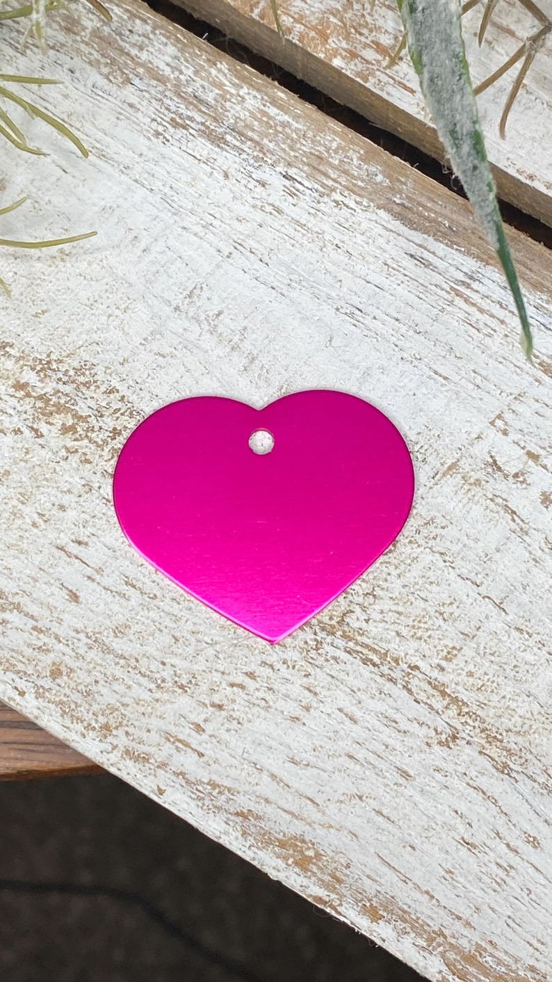May include: A bright pink heart-shaped metal tag with a hole for a ring or chain.