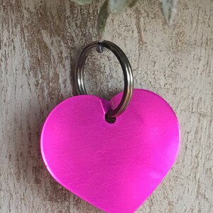 May include: A bright pink heart-shaped keychain with a silver key ring.