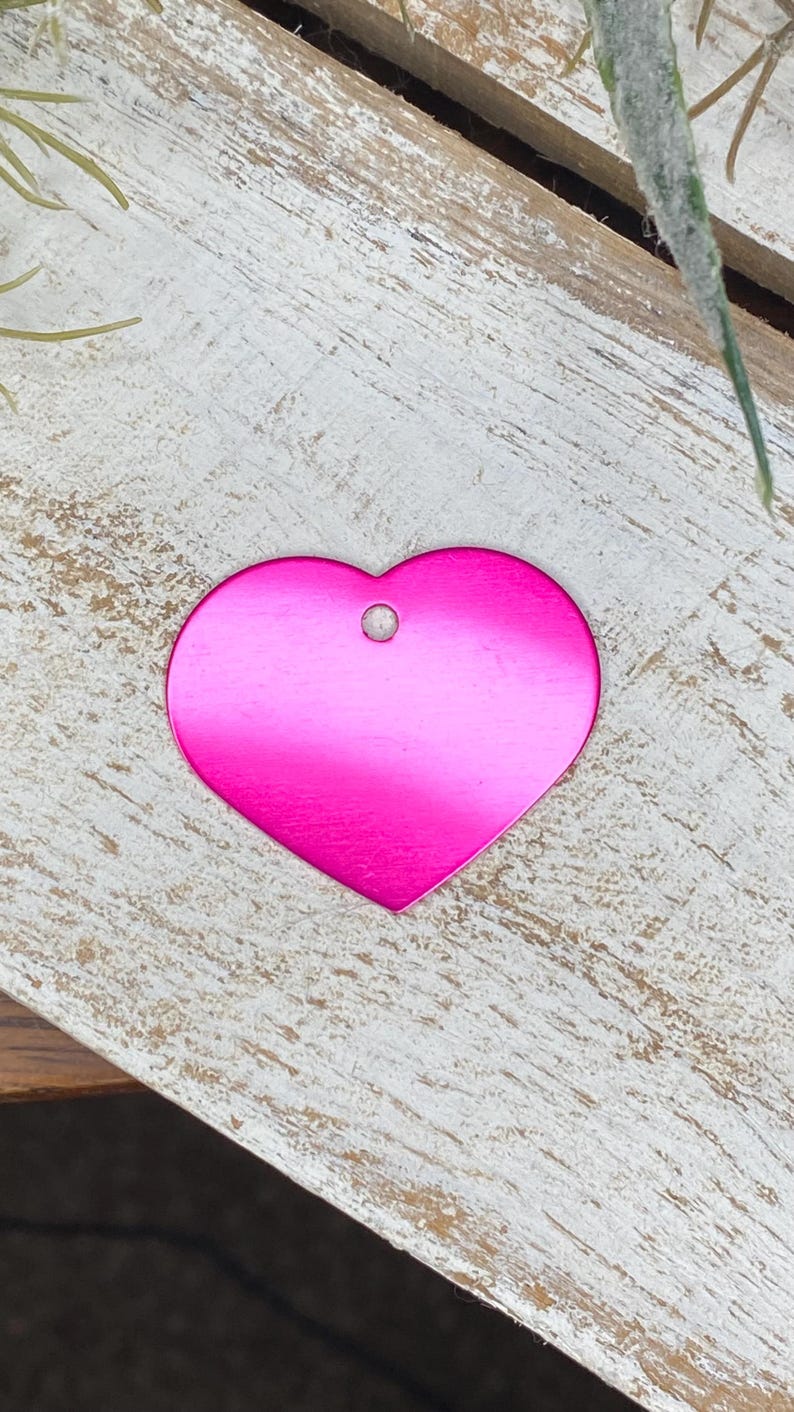 May include: A bright pink heart-shaped metal tag with a hole at the top.