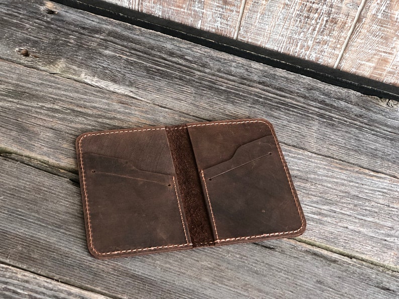 May include: A brown leather wallet with multiple pockets and stitching around the edges.