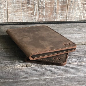 May include: Two brown leather passport holders with initials "MK" and "EK" embossed on the front.