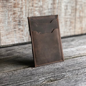 K&ouml;nnte beinhalten: Eine braune Ledergeldb&ouml;rse mit mehreren Kartenf&auml;chern und einem gro&szlig;en Fach. Die Geldb&ouml;rse hat einen Used-Look und ist mit braunem Garn vern&auml;ht.