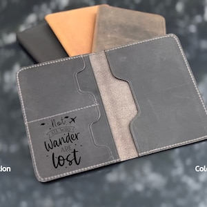 May include: Gray leather passport holder with a stitched edge and a quote that reads "Not all who wander are lost" with a small airplane icon.