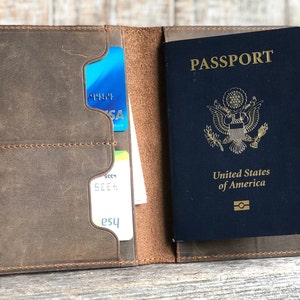 May include: A brown leather passport holder with a passport inside. The passport is a US passport with the words "PASSPORT" and "United States of America" printed on the cover.