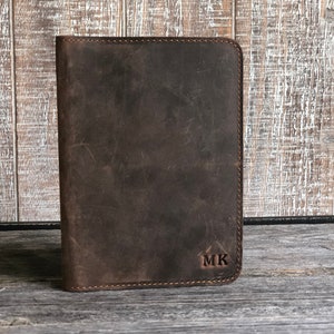 May include: A brown leather notebook with a stitched edge and the initials "MK" embossed on the front.
