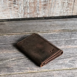 May include: A brown leather wallet with the initials "L.M." embossed on the front.