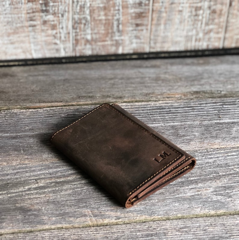 May include: A brown leather wallet with the initials "L.M." embossed on the front.