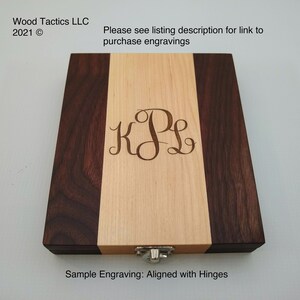 May include: A wooden box with a walnut and maple wood grain pattern. The box has a hinged lid and a metal latch. The box is engraved with the initials "KPL" and the text "Sample Engraving: Aligned with Hinges".