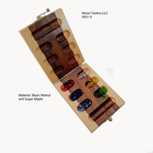 May include: A wooden game board with a hinged lid. The board is made of black walnut and sugar maple. The board is open and shows the game pieces, which are small glass marbles in various colours. The board is labelled "Wood Tactics LLC 2021 &copy;".