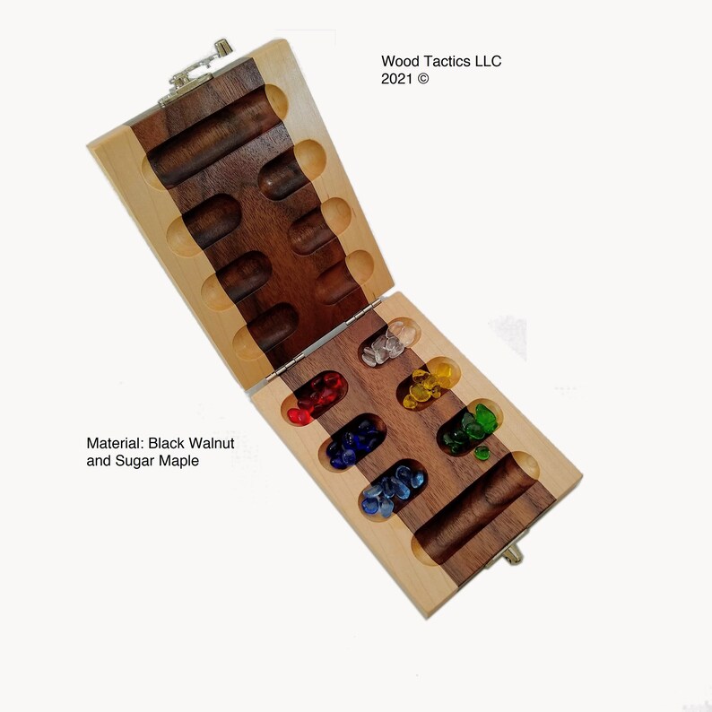 May include: A wooden game board with a hinged lid. The board is made of black walnut and sugar maple. The board is open and shows the game pieces, which are small glass marbles in various colours. The board is labelled "Wood Tactics LLC 2021 &copy;".