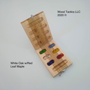 May include: A wooden game board with a hinged lid, made of white oak with red leaf maple. The board is open, revealing six rows of small glass beads in different colours: green, clear, blue, yellow, red, and blue.