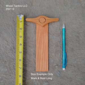 Pode incluir: Uma ferramenta de madeira para marcar e segurar comprimentos longos. A ferramenta tem aproximadamente 18 cm de comprimento e possui uma pequena pega no topo. O texto "Size Example Only Mark & Hold Long" est&aacute; impresso abaixo da ferramenta.