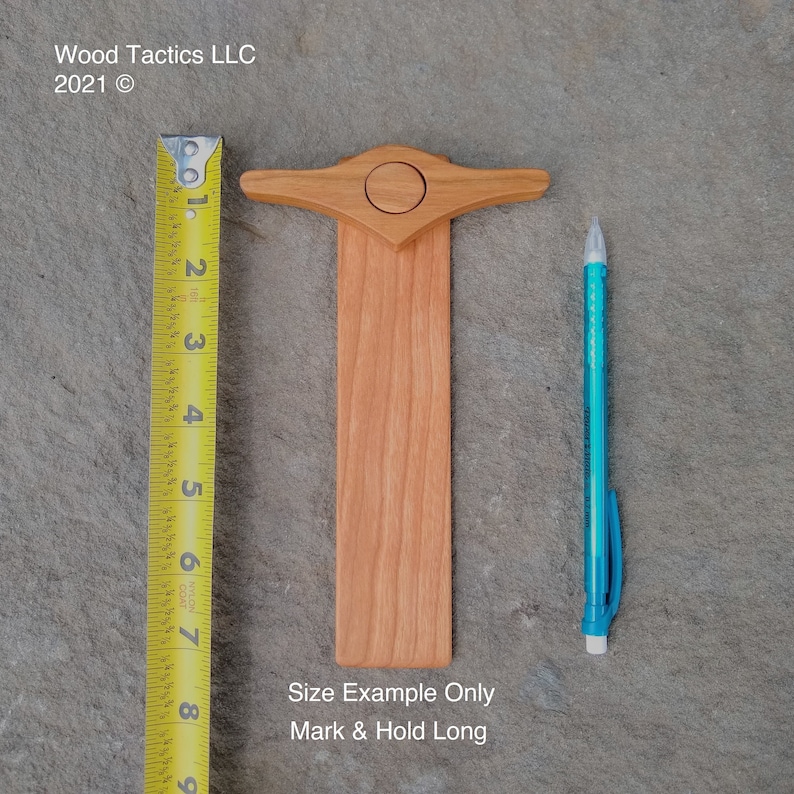 Pode incluir: Uma ferramenta de madeira para marcar e segurar comprimentos longos. A ferramenta tem aproximadamente 18 cm de comprimento e possui uma pequena pega no topo. O texto "Size Example Only Mark & Hold Long" est&aacute; impresso abaixo da ferramenta.