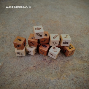 May include: A set of 10 wooden dice with various nature-themed symbols, including fish, leaves, flowers, and wheat. The dice are a mix of light and dark brown wood.