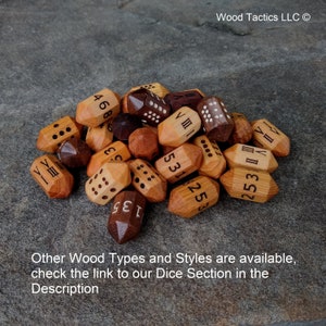 Puede incluir: Un mont&oacute;n de dados de madera con varios n&uacute;meros y n&uacute;meros romanos grabados en ellos. Los dados son de tonos marrones y madera natural. El texto "Wood Tactics LLC" es visible en la esquina superior derecha de la imagen.